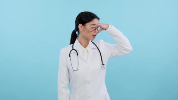 身穿医疗外套的不满意的白人女医生闻到了难闻的气味 被这种气味震惊了 并在蓝色的背景上捂住了鼻子 医学上的问题恶心的香气 — 图库视频影像