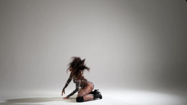 エレガントなカーリーハイレッドの女性は ハイヒールで洗練されたハイヒールで自然な白い背景を踊ります エネルギッシュな動きは 優雅さ 洗練された魅力 柔軟性の両方の証です — ストック動画