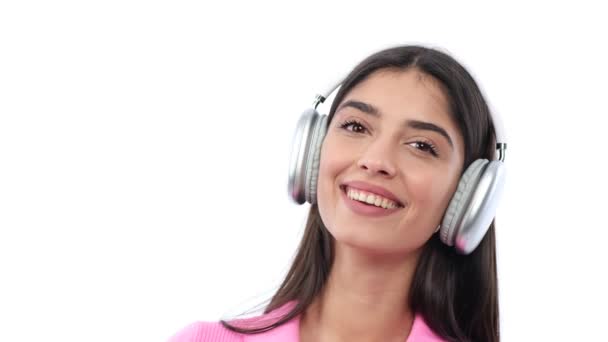 一个满意的 快乐的高加索女人的画像 她用耳机听音乐 躺在白色背景上 — 图库视频影像