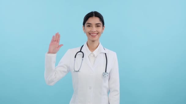 Lächelnde Kaukasische Ärztin Auf Blauem Grund Winkt Und Grüßt Die — Stockvideo