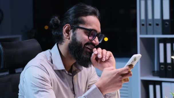 Positivo Indiano Empresário Mensagens Telefone Rindo Enquanto Trabalhava Escritório Noite — Vídeo de Stock