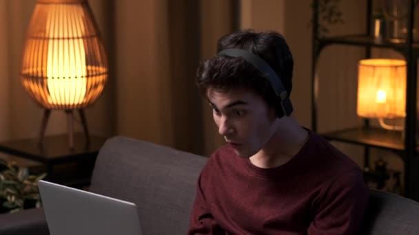 Νεαρός Άνδρας Φορητό Υπολογιστή Ακουστικά Σερφάρει Στο Διαδίκτυο Εκπλήσσεται Και — Αρχείο Βίντεο