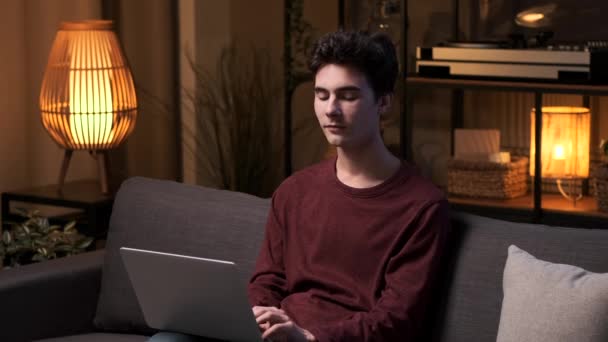집에서 저녁에 소파에 앉아있는 일이나 공부를위한 노트북을 사용하여 행복한 코카서스 — 비디오