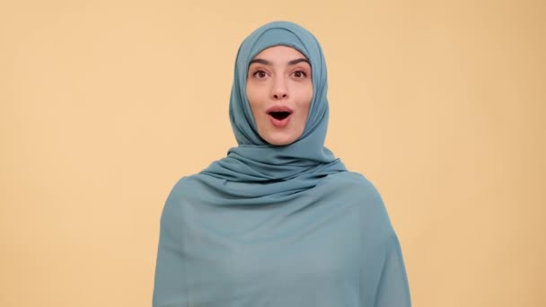 一个穿着传统头巾的令人惊讶的穆斯林妇女的画像 在米色的背景上惊叹不已 庆祝成功 积极反应 女性获奖者 — 图库视频影像