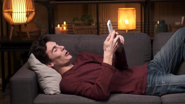 Homem Está Relaxando Noite Com Seu Telefone Navegando Internet Rindo — Vídeo de Stock