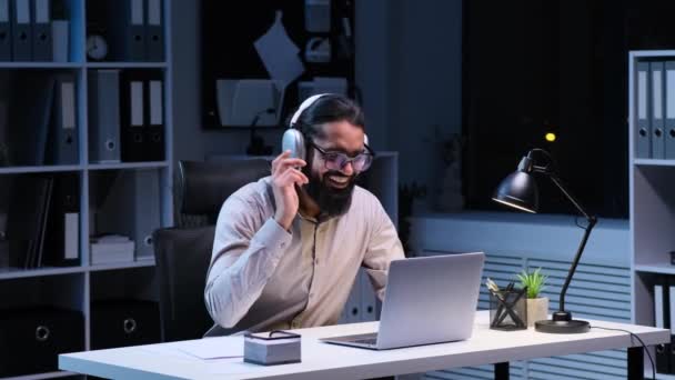 Indický Spokojený Podnikatel Pracuje Laptopem Poslouchá Hudbu Sluchátkách Noční Kanceláři — Stock video