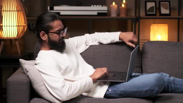 Relaxado Satisfeito Indiano Homem Relaxante Sofá Com Laptop Noite Sala — Vídeo de Stock