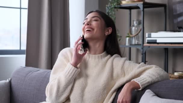 年轻的白人女人在电话里聊天 在家里客厅的沙发上大笑 远距离交谈 在家休息 休闲活动概念 — 图库视频影像