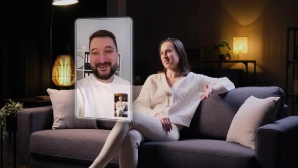 笑顔の白人男性と女性 友人や家族のカップルは 近代的な拡張現実のオンライン技術 ホログラフィックディスプレイを使用して 夜の自宅でビデオ通話で話します リモートコミュニケーションコンセプト — ストック動画