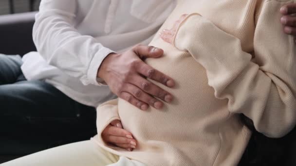 夫妻俩手挽手 坐在沙发上抚摸怀孕的肚子 预产期和预产期 分娩前准备 孕期享受 — 图库视频影像