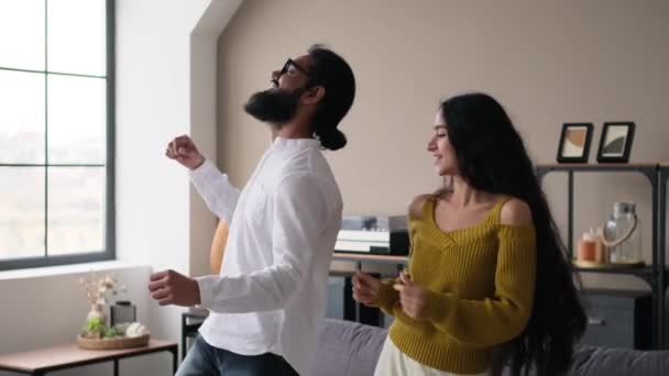 若い幸せなインドのカップルは 自宅でリラックスしながら音楽に踊り 一緒に自由な時間を過ごしました 笑って アクティブなフリータイムを楽しむ — ストック動画