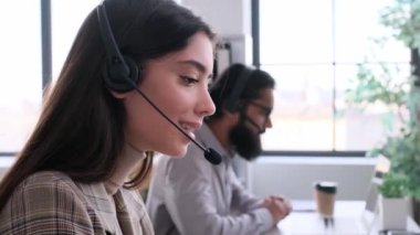 Gülümseyen ve neşeli beyaz kadın müşteri danışmanı ofiste çalışıyor, kulaklıkla konuşuyor, tüketiciyle iletişim kuruyor. Telekomünikasyon, online çağrı kavramı.