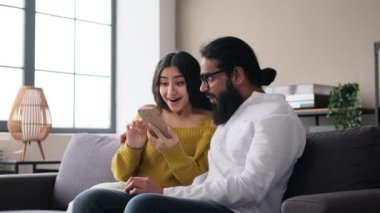 Genç Hintli çift boş zamanlarını telefonlarıyla, internette gezinerek internet üzerinden iletişim kurarak ve kahkahalarla geçirir. Oturma odasındaki kanepede dinlenir..