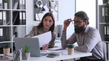 Çalışma arkadaşları modern ofisteki masa başında kağıtlar, dizüstü bilgisayarlar ve hesap makineleriyle birlikte çalışıyorlar. Analiz, inceleme ve araştırma belgeleri, finans hesaplama, iş stratejisi geliştirme. Takım çalışması konsepti.