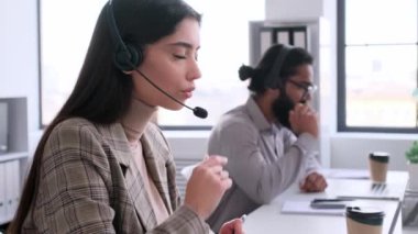 Ofisteki müşterilerle iletişim kurmak için kulaklık kullanan konsantre beyaz kadın çevrimiçi destek görevlisi. Yardım hattı danışmanı, iletişim merkezi çalışanı.