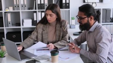 Birkaç iş arkadaşı beyin fırtınası yapıyor, evrak analizi yapıyor iş stratejisi geliştiriyor, iş görüşmesi yapıyor, modern ofiste masa başında oturuyor. Takım çalışması ve işbirliği kavramı.