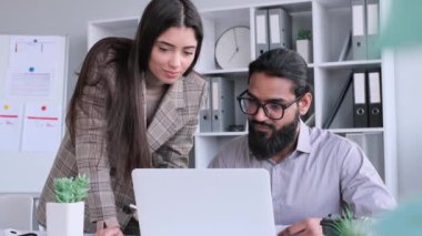 Dost canlısı çok uluslu iş arkadaşları, kadın ve erkek, dizüstü bilgisayarla birlikte çalışıyorlar ve ofiste konuşuyorlar. İş görüşmesi ve tartışma, proje brifingi.