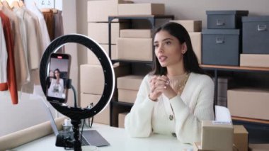 Neşeli kadın vlogger video yayınını akıllı telefon kullanarak kaydediyor, sosyal medyada izleyicilerle iletişim kuruyor, çevrimiçi ofis masasında oturuyor..