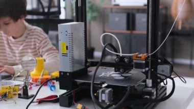 Genç beyaz öğrenci evde dizüstü bilgisayar ve 3D yazıcı ile ev ödevi yapıyor. 3D mühendislik, programlama, proje planlama kavramı.