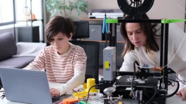 Ana-oğul evdeki laboratuarda 3D yazıcıyı araştırıyor. 3D yazıcı ayrıntıları, mekanizma bileşenleri analiz ediliyor. Aile çalışması, DIY konsepti.