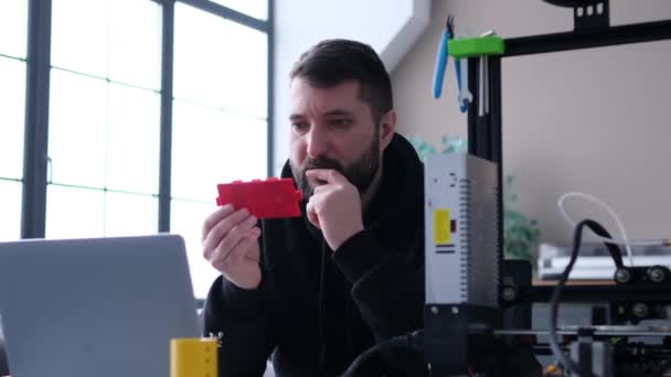 技術者コーカサスの人間は リビングルームの机に座ってラップトップを使用して 3Dプリンターで印刷するプロジェクトの品質を制御します コンセプトの開発と構築 — ストック動画