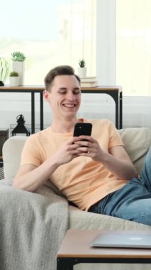 Kafkasyalı bir adam rahat bir şekilde bir koltuğa oturmuş, akıllı telefonuna dalmış. Rahat bir duruş ile, o kolaylıkla dengeler cihazı elinde, parmakları hafifçe dokunur ve kaydırır.