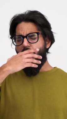 Yorgun sakallı genç adamın portresi kollarını uzatıp esniyor ve beyaz arka planda tek başına duruyor.