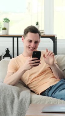 Oturma odasındaki rahat koltukta oturan mutlu adam akıllı telefonuna dalmış. Cihazının içeriğiyle ilgilenirken yüzünde sıcak bir gülümseme belirdi. Gördüklerinden keyif alıyordu..