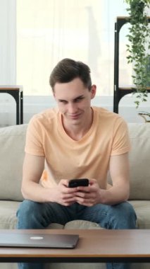 Kafkasyalı bir adam, kameraya bakarken neşe ve sıcaklık saçıyor. Oda rahat bir zemin sağlıyor, rahatlık ve samimiyet hissi yayıyor. Adamın gerçek gülümsemesi yüzünü parlatıyor..