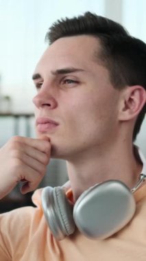 Adam evindeki rahat koltukta rahat bir şekilde oturuyor. Derin düşüncelere dalmış, kaşları hafifçe çatılmış ve bakışları uzak bir noktaya odaklanmış..