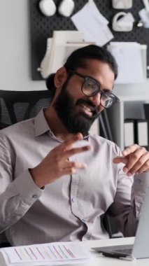 Hintli işadamı ofiste mola veriyor, neşeli bir video görüşmesi yapıyor. Ofis kıyafetleri içinde, neşeli ifadeler ara sırasında bir neşe ve bağlantı hissi veriyor..