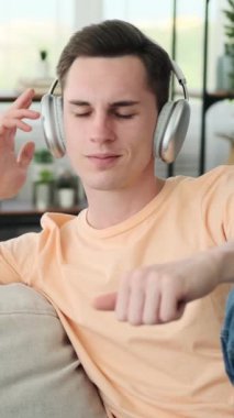 Huzurlu bir ortamda rahat rahat rahat koltukta oturan bir adam. Bir çift şık kulaklık takıyor, kendini müzik dünyasına kaptırma niyetini gösteriyor..