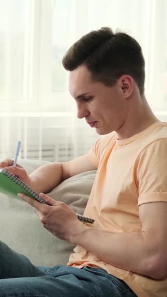 Hombre Sentado Cómodo Sofá Profundamente Absorto Escritura Cuaderno Frente Está — Vídeos de Stock