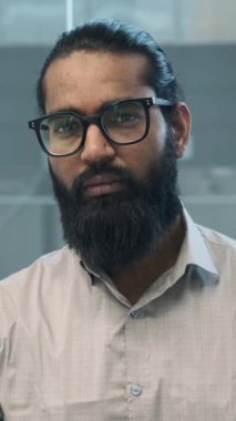 Büyüleyici bir portrede, Hintli bir işadamı kameraya bakarken sıcak bir gülümseme sahneyi alır. Onun dostça ifadesi güven ve yakınlık yayar..