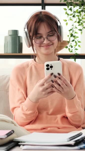 Uma Adolescente Sorridente Senta Confortavelmente Sofá Absorvida Pelo Telefone Com — Vídeo de Stock