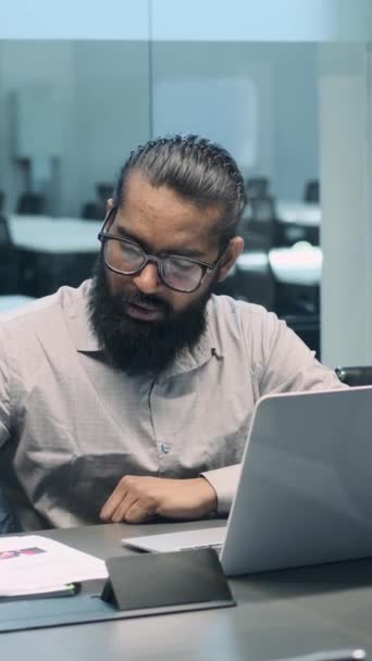 在他井井有条的办公桌前 一位内省的印度商人沉浸在他的笔记本电脑工作中 他带着若有所思的表情深入探讨自己的任务 — 图库视频影像