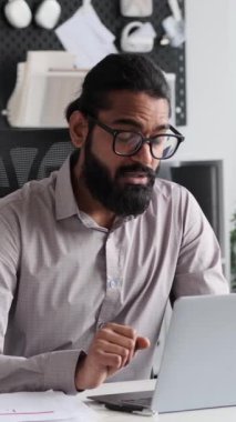 Hintli işadamı coşkuyla canlı bir ofis ortamında video görüşmesiyle iletişim kuruyor. Kurumsal tarzda dizilmiş, arkadaş canlısı tavırlar sanal etkileşime biraz sıcaklık katar..