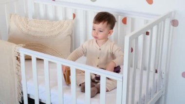 Aktif ve meraklı beyaz çocuk çocuk çocuk odasında beşikte oturan tahta atlarla oynuyor. Neşeli bebeklik konsepti.