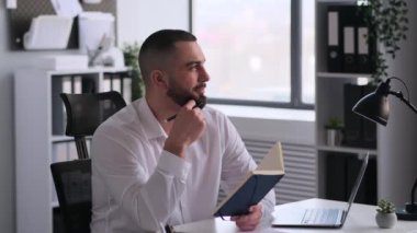 Neşeli Kafkasyalı erkek çalışanın takvimde günlük gündem planlaması, düzenleyiciyle hatırlatma yazması. Olay planı ya da programı oluşturuluyor.