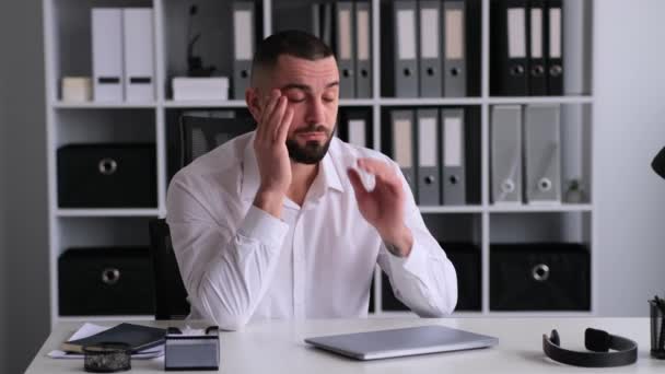 不健康的白人男性办公室职员患有头痛 按摩太阳穴 坐在现代办公室的办公桌前 疾病概念 — 图库视频影像