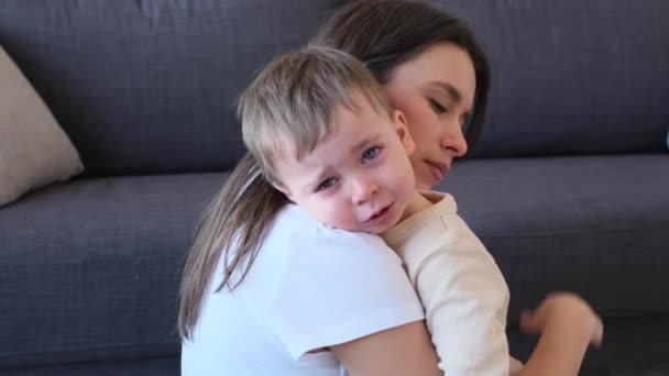 在家里的客厅里 照顾着白人年轻的母亲 拥抱着她哭泣的小儿子 不满和烦躁的幼儿 泪流满面 — 图库视频影像