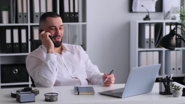 友好的な白人男性オフィスワーカーは 顧客と話す携帯電話を使用して オフィスの机に座っています セールススペシャリストコンサルティングクライアント — ストック動画