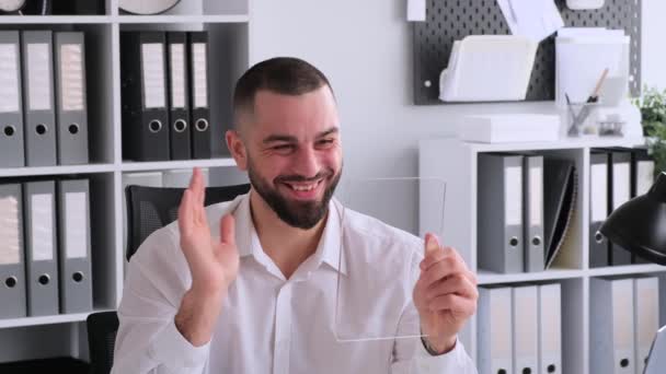 ビデオ通話のための未来的な透明なタブレットを使用して幸せな白人ビジネスマン 同僚や友人と話し 手を振って笑顔で挨拶する 拡張現実の概念 — ストック動画