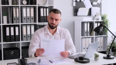 Belgeler ve dizüstü bilgisayarla çalışan konsantre beyaz erkek serbest çalışan. Mali ve muhasebe bilgilerinin analiz edilmesi ve planlanması.
