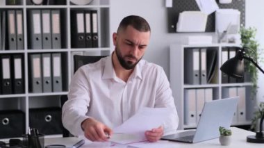 Ciddi bir Kafkasyalı işadamı ofiste çalışırken belge ya da bütçe imzalıyor. Evrak işleriyle uğraşıyor, finansal bilgileri analiz ediyor..