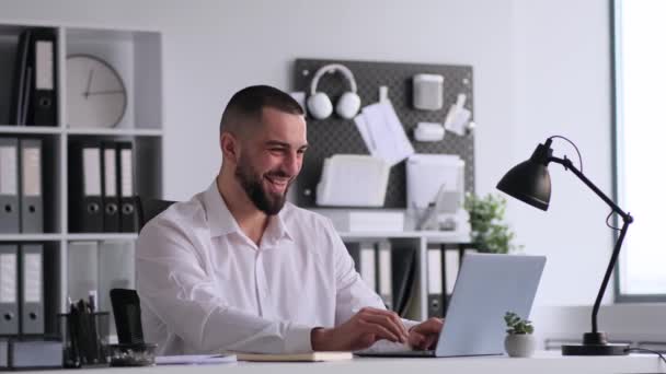 与笔记本电脑一起工作的白人男性员工获得了好消息 并庆祝自己的成就 坐在现代办公室的办公桌前 — 图库视频影像