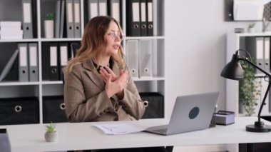 Kafkasyalı kadın patron, bilgisayarla çevrimiçi toplantı sırasında astlarını tartışıyor, belgeleri masaya atıyor, ofiste çalışıyor. İnternet video oturumu kavramı.