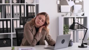 Ofiste dizüstü bilgisayarla çalışırken boynu ağrıyan üzgün ve hoşnutsuz beyaz kadın çalışan. Masaj boynu, rahatlama gerilimi. Bitkinlik, yorgunluk, iş baskısı konsepti.
