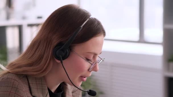 Σοβαρή Γυναίκα Καυκάσια Τηλεφωνήτρια Που Εργάζεται Στο Γραφείο Χρησιμοποιώντας Ακουστικά — Αρχείο Βίντεο