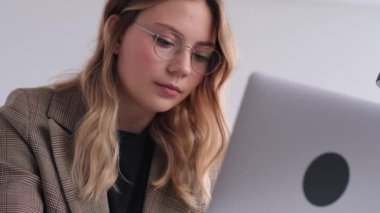 Ofiste dizüstü bilgisayarla çalışan beyaz bir kadının portresi. Finans bilgileri okunuyor, beyin fırtınası yapılıyor, açılışa hazırlanılıyor.